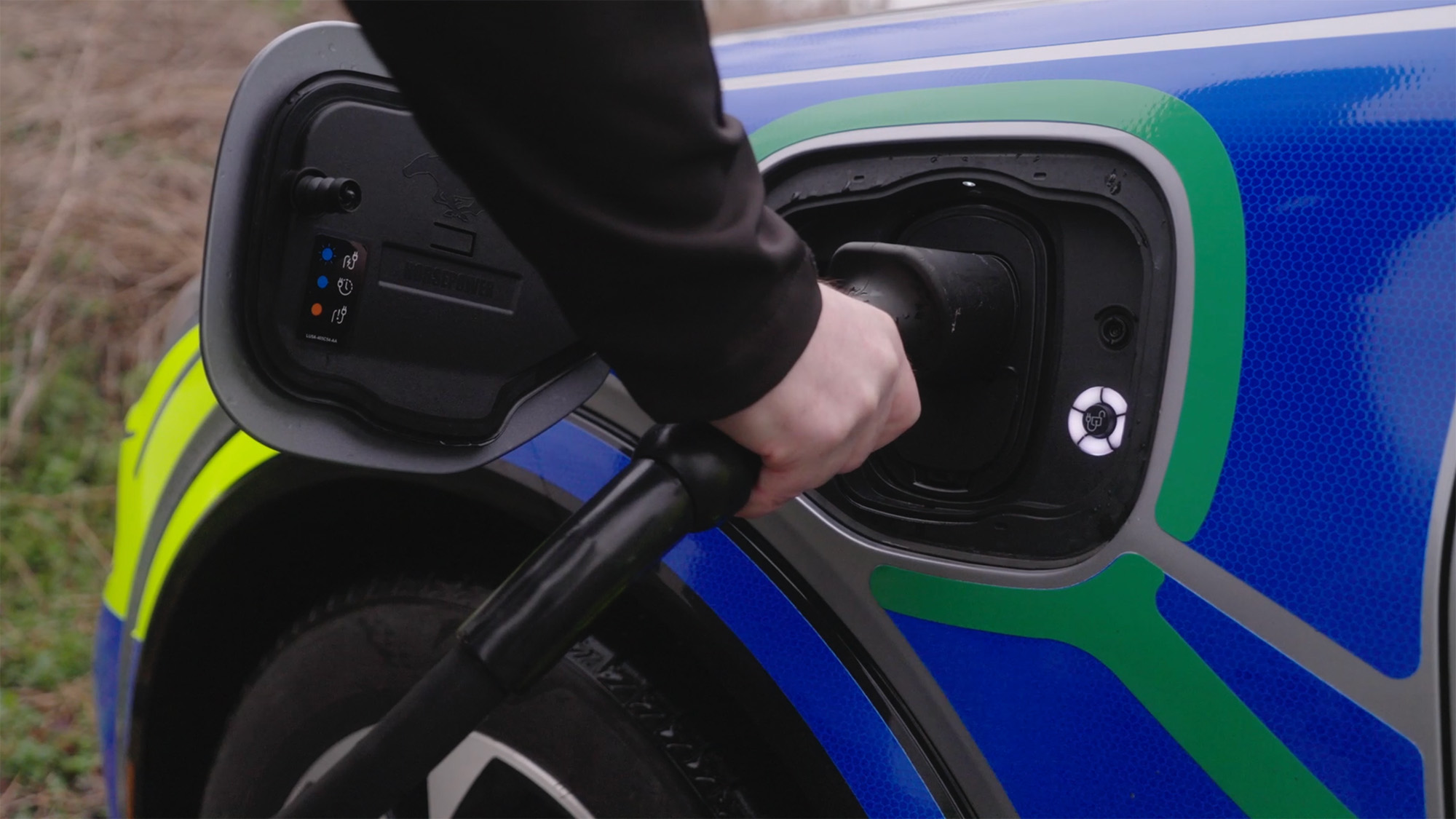 Close-up of an electric vehicle being plugged into a charging port by hand, highlighting modern EV charging technology