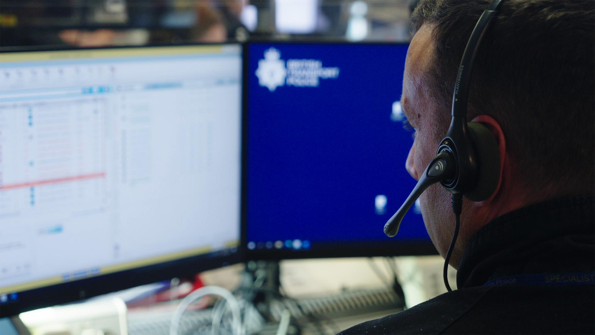Specialist operations staff member wearing a headset and monitoring multiple computer screens in a control room