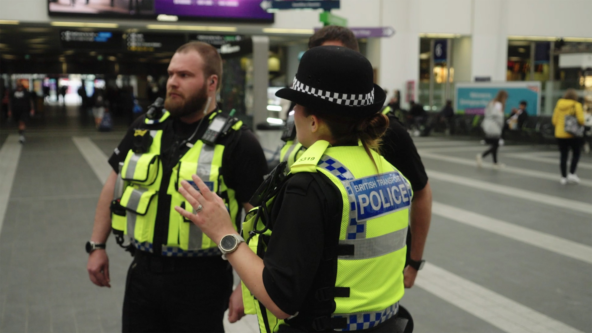 Police officers in high-visibility vests standing inside Birmingham New Street station