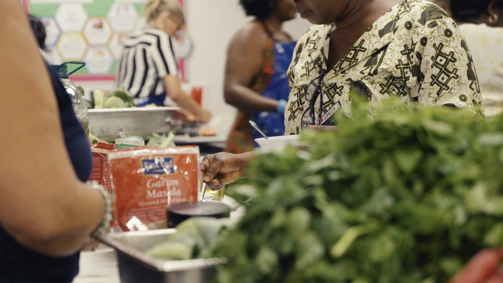 People taking part in a cooking activity with fresh vegetables and spices laid out on the table