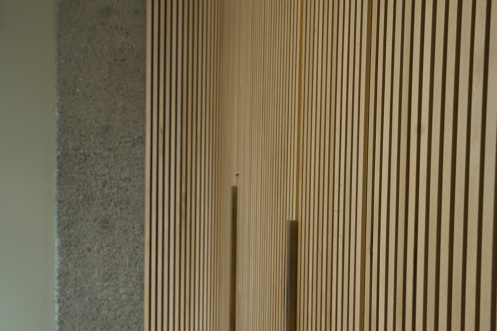 Close‑up of vertical wooden slats beside a textured concrete wall in a modern architectural interior