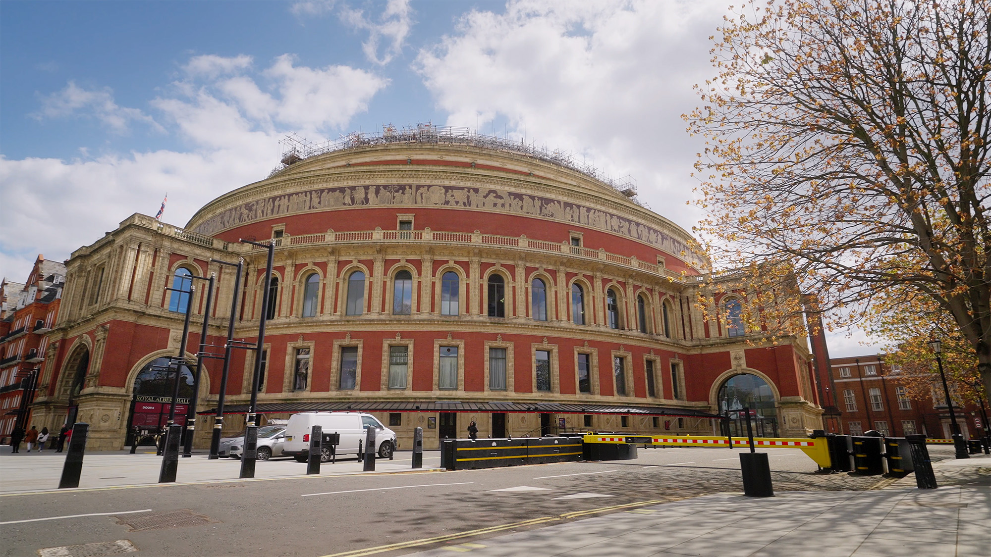 Exterior of the Royal Albert Hall with red brick façade, arched windows and scaffolding along the roofline