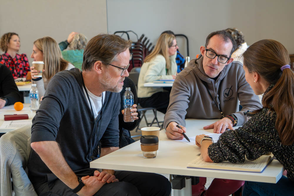 Participants seated around a table reviewing notes and discussing ideas during a training workshop
