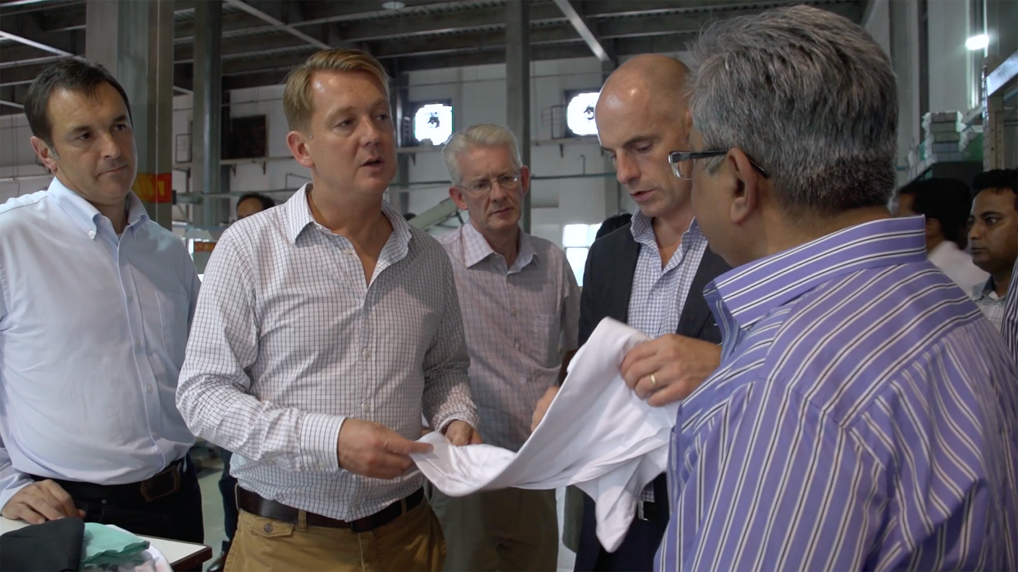 Four people in a factory examining a piece of fabric during a production or quality check