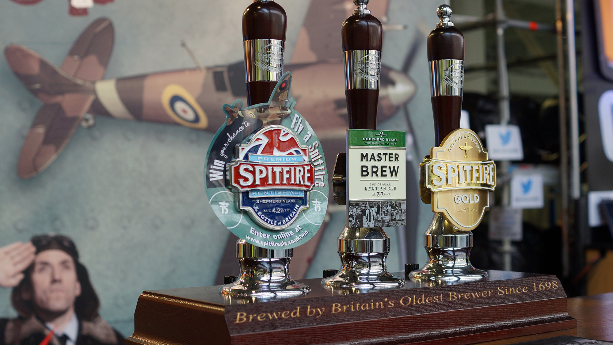 Beer taps for Spitfire and Master Brew ales with a Spitfire aircraft poster in the background