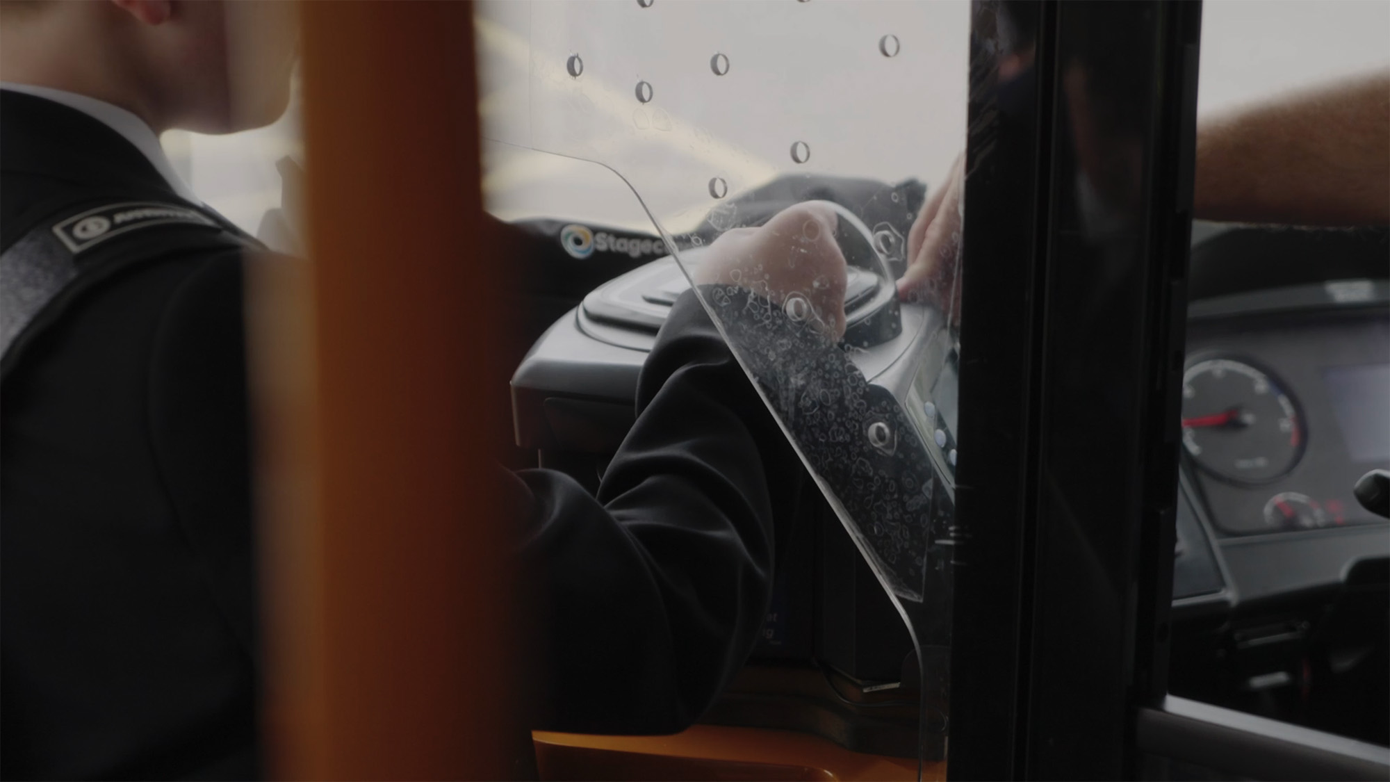 Passenger scanning a bus pass on a Stagecoach with a bus driver behind a protective screen