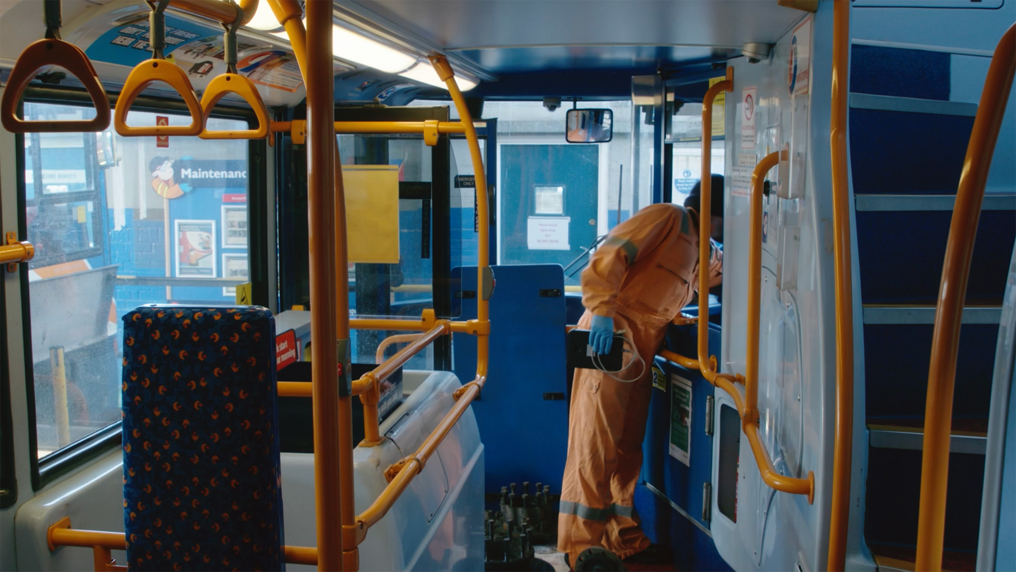 Engineer in protective suit and gloves inspecting the driver’s area inside a bus