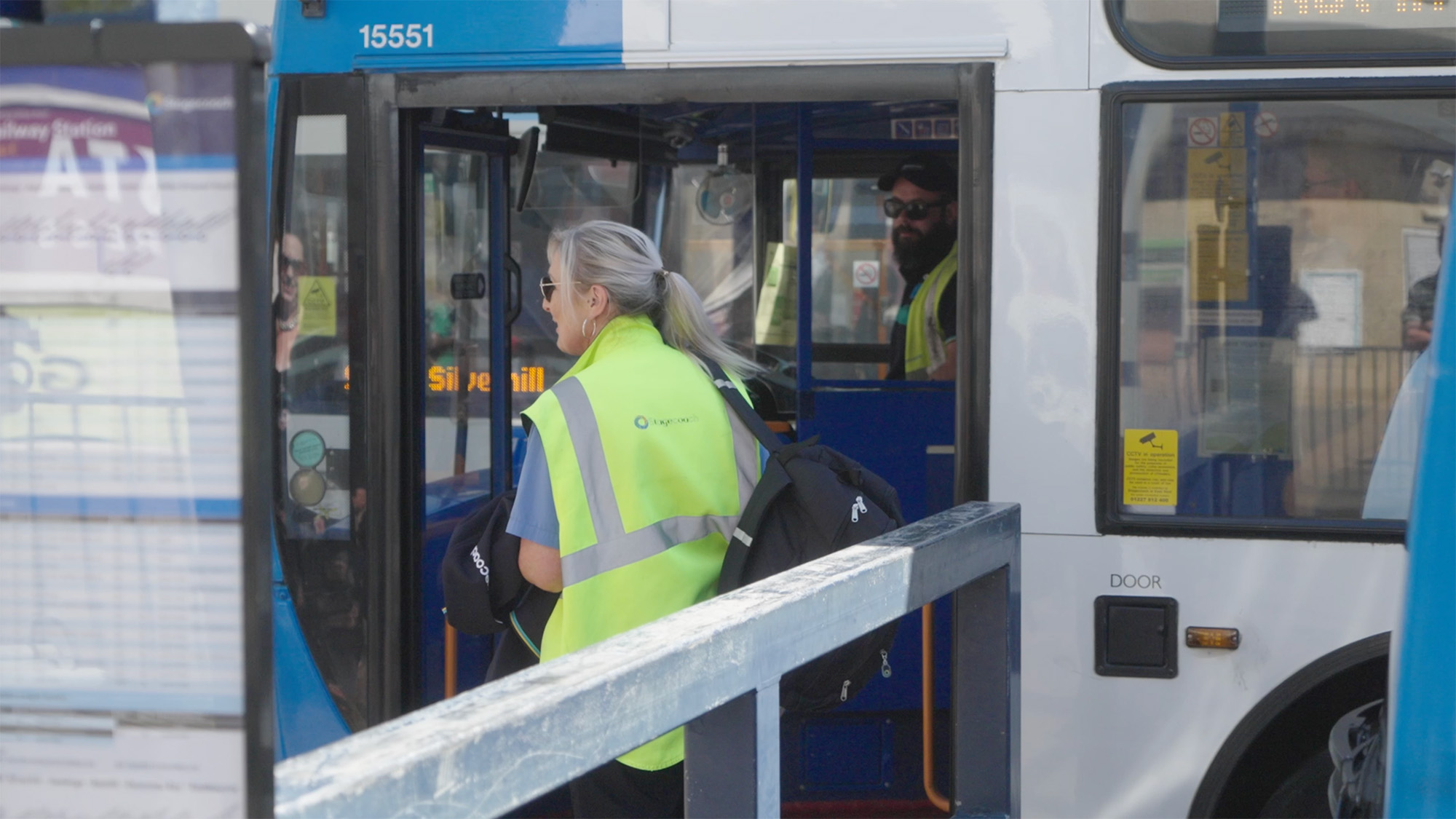 Two staff members in high‑visibility vests talking at the entrance of a Stagecoach bus